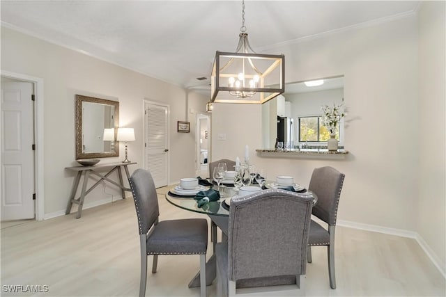 dining space with light wood-type flooring, baseboards, and a notable chandelier