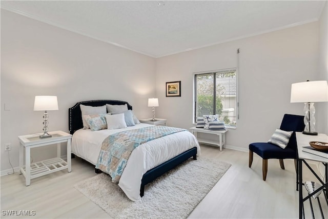 bedroom featuring light wood-type flooring, ornamental molding, and baseboards
