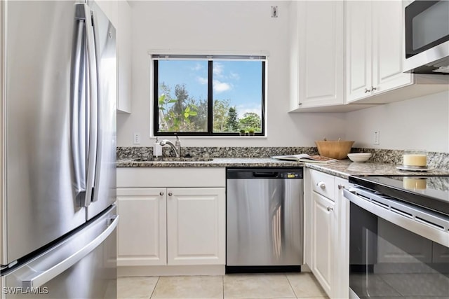 kitchen with stainless steel appliances, a sink, white cabinetry, and stone counters