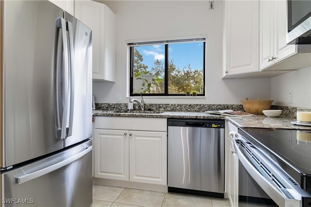 kitchen with stainless steel appliances, a sink, white cabinetry, stone counters, and light tile patterned floors