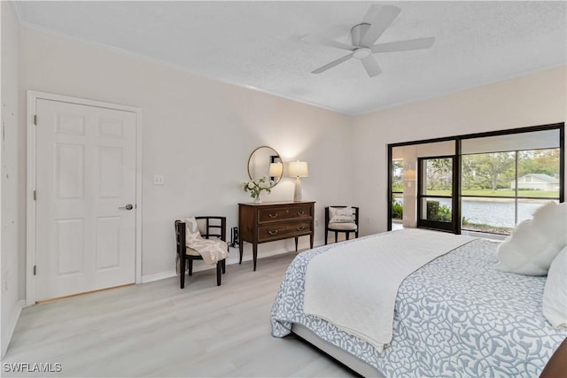 bedroom featuring light wood-style floors, access to exterior, a water view, and baseboards