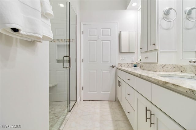 bathroom with a stall shower, double vanity, and tile patterned flooring