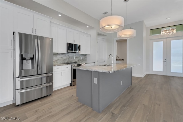 kitchen featuring white cabinetry, stainless steel appliances, light stone counters, and pendant lighting