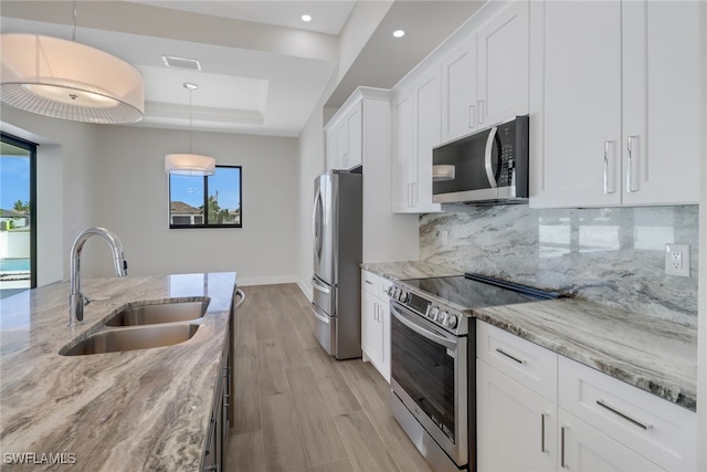 kitchen featuring white cabinets, light stone countertops, sink, decorative light fixtures, and stainless steel appliances