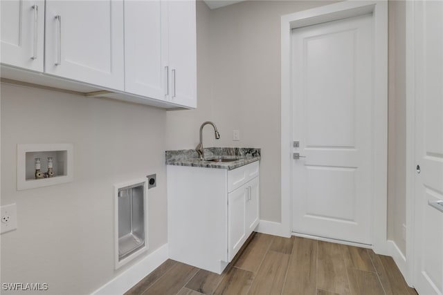 laundry area featuring hookup for a washing machine, hookup for an electric dryer, sink, light wood-type flooring, and cabinets