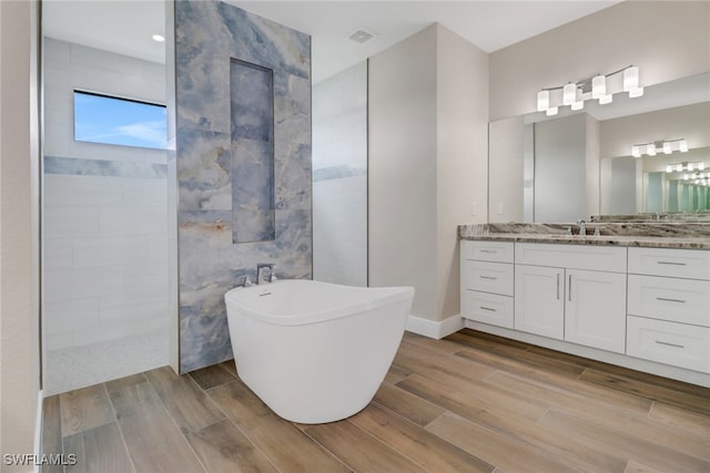 bathroom with vanity, hardwood / wood-style floors, and plus walk in shower