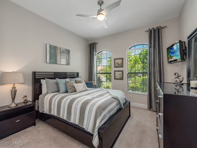 bedroom with multiple windows, ceiling fan, and light carpet