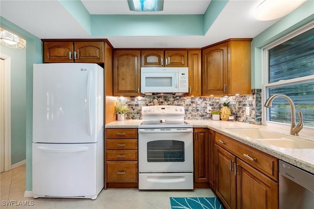 kitchen with light stone countertops, white appliances, tasteful backsplash, sink, and light tile patterned floors