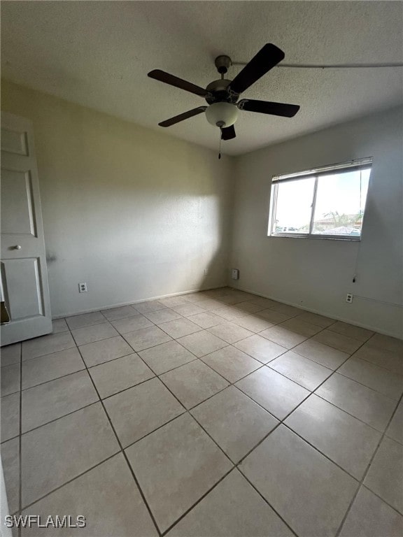 tiled spare room featuring ceiling fan