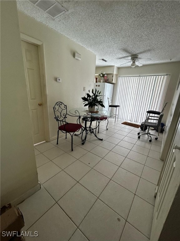 unfurnished dining area featuring a textured ceiling, ceiling fan, and light tile patterned floors