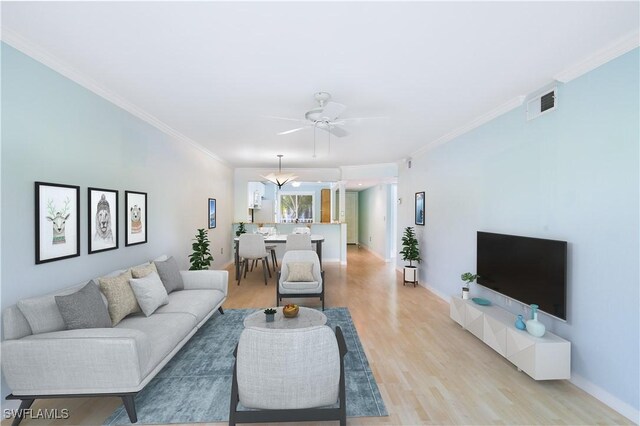 living room featuring light wood-type flooring, ornamental molding, and ceiling fan