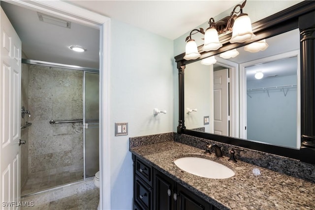 bathroom featuring visible vents, a spacious closet, toilet, a stall shower, and vanity