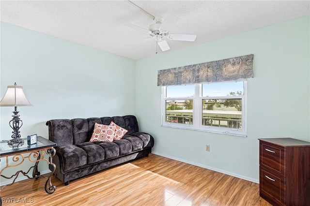 living room featuring light hardwood / wood-style floors, a textured ceiling, and ceiling fan