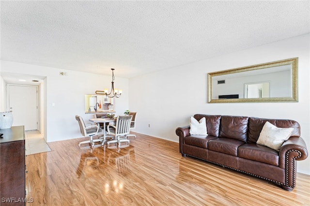 living room featuring light hardwood / wood-style floors, a textured ceiling, and an inviting chandelier