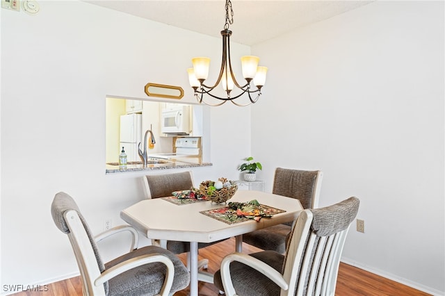 dining area featuring wood-type flooring and an inviting chandelier