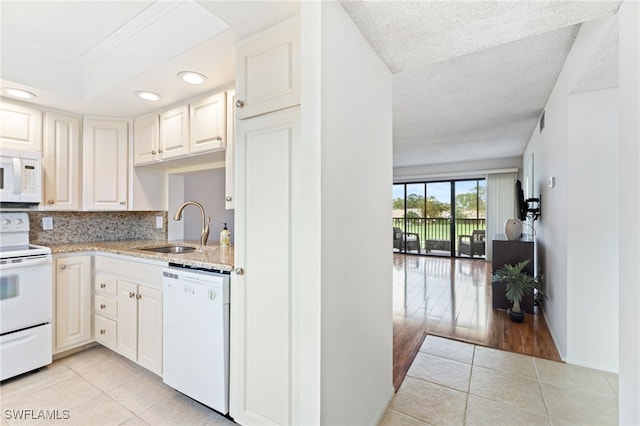 kitchen with light wood-type flooring, a textured ceiling, sink, white cabinets, and white appliances