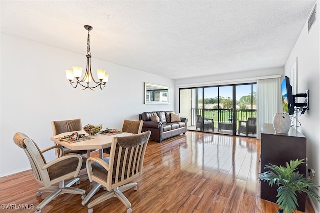 dining area featuring hardwood / wood-style floors, a notable chandelier, and a textured ceiling