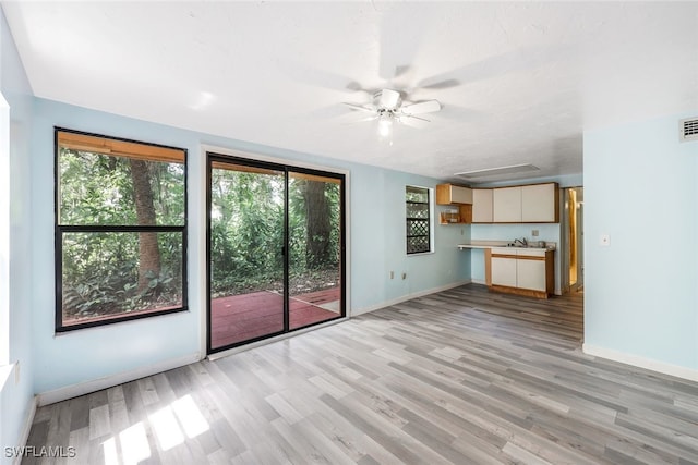18191 Slater Rd, North Fort Myers, FL 33917 - unfurnished living room featuring baseboards, a ceiling fan, light wood finished floors, and plenty of natural light