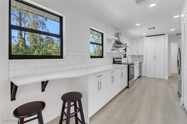 kitchen featuring a breakfast bar area, a wealth of natural light, white cabinets, and stainless steel appliances