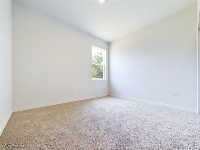 unfurnished room featuring lofted ceiling and carpet flooring