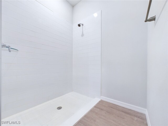 bathroom featuring hardwood / wood-style flooring and a tile shower