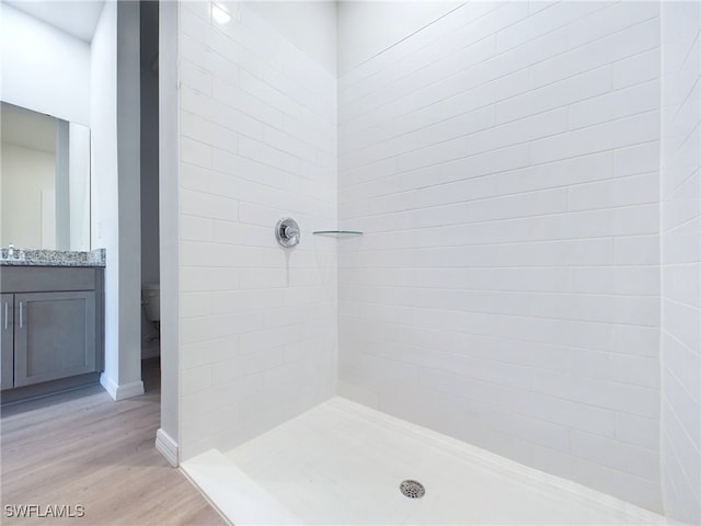 bathroom featuring wood-type flooring, a tile shower, and vanity