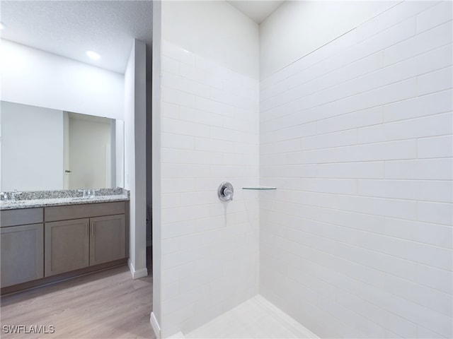 bathroom featuring tiled shower, vanity, hardwood / wood-style floors, and a textured ceiling