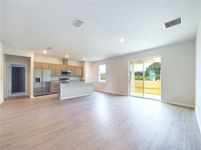 interior space featuring light hardwood / wood-style flooring, light brown cabinetry, appliances with stainless steel finishes, a kitchen island with sink, and sink