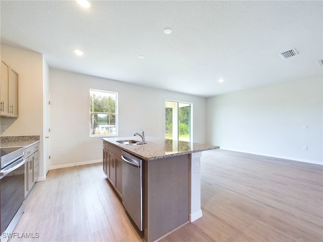 kitchen featuring dishwasher, a kitchen island with sink, light hardwood / wood-style floors, sink, and stove