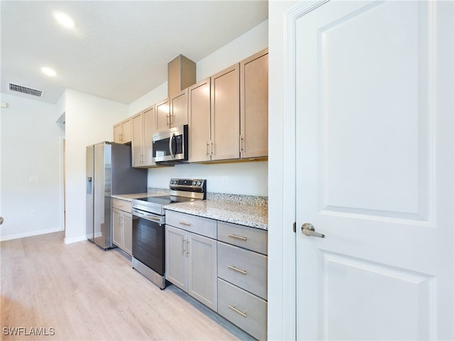 kitchen featuring light wood-type flooring, light stone counters, light brown cabinets, and stainless steel appliances