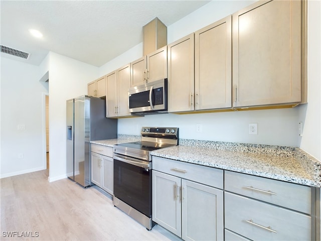 kitchen featuring light stone countertops, stainless steel appliances, and light hardwood / wood-style floors