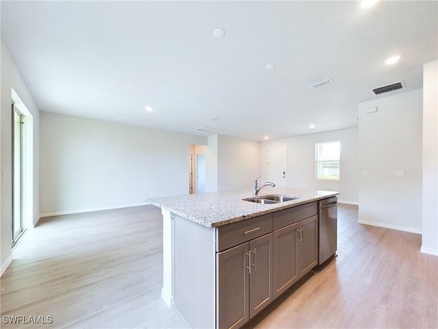 kitchen with a kitchen island with sink, stainless steel dishwasher, sink, and light hardwood / wood-style floors