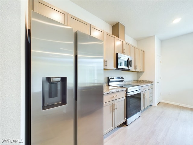 kitchen with light hardwood / wood-style flooring, light brown cabinetry, light stone countertops, and appliances with stainless steel finishes