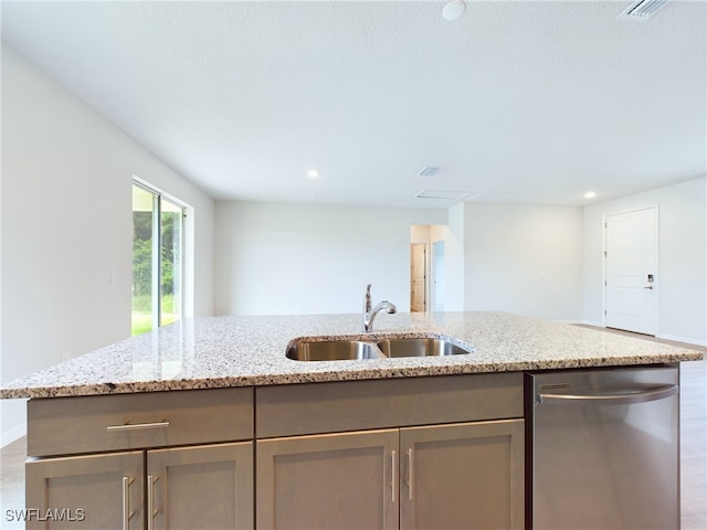 kitchen with a kitchen island with sink, light stone counters, stainless steel dishwasher, and sink