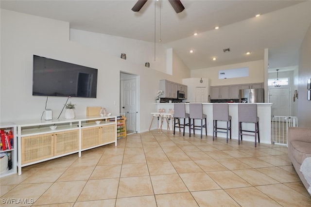 tiled living room featuring ceiling fan and high vaulted ceiling