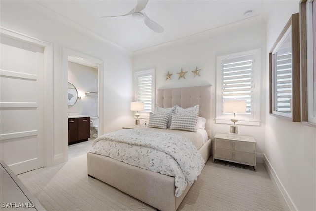 bedroom featuring crown molding, ensuite bathroom, a ceiling fan, light carpet, and baseboards