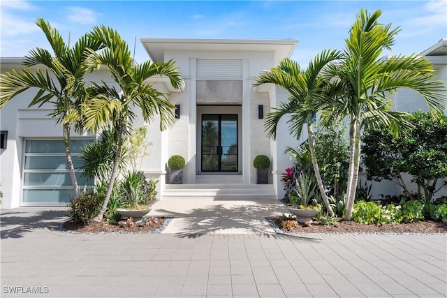 property entrance with driveway, an attached garage, and stucco siding