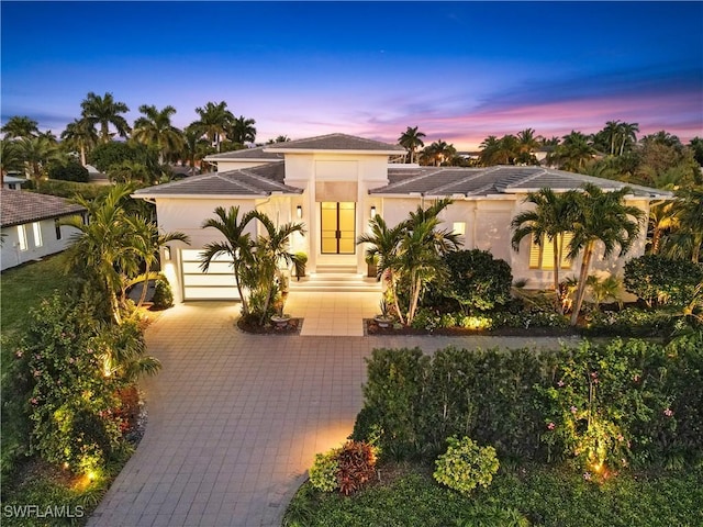 view of front of home with a garage, decorative driveway, and stucco siding