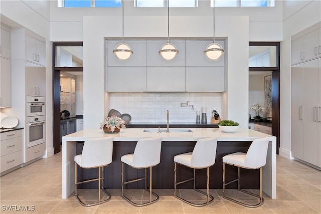 kitchen with hanging light fixtures, modern cabinets, a high ceiling, and light countertops