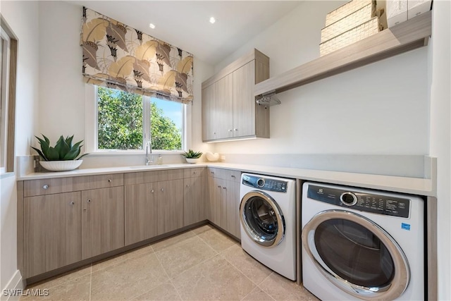 washroom featuring cabinet space, light tile patterned floors, a sink, and washing machine and clothes dryer