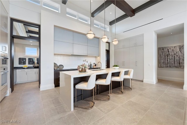 4220 Crayton Rd, Naples, FL 34103 - kitchen featuring decorative backsplash, a breakfast bar area, a towering ceiling, light tile patterned flooring, and beam ceiling