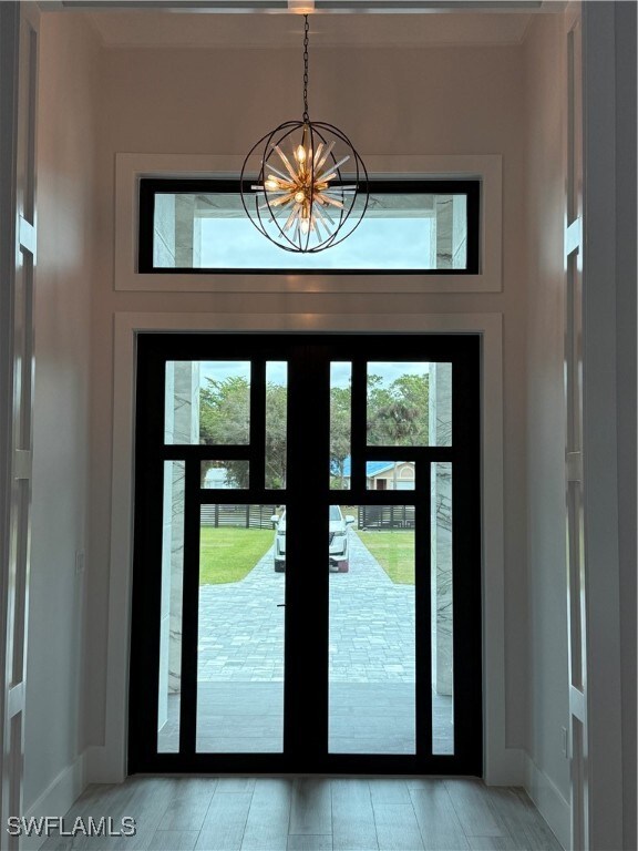 doorway to outside with light hardwood / wood-style floors, french doors, and a chandelier