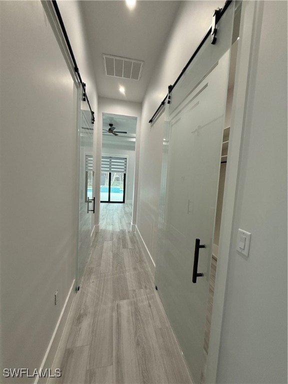 corridor with a barn door and light wood-type flooring