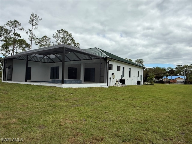 rear view of property featuring a lawn and glass enclosure