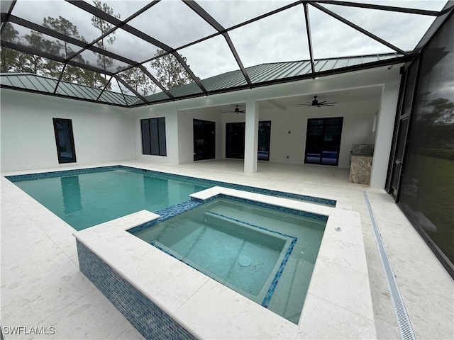 view of swimming pool with glass enclosure, ceiling fan, an in ground hot tub, and a patio