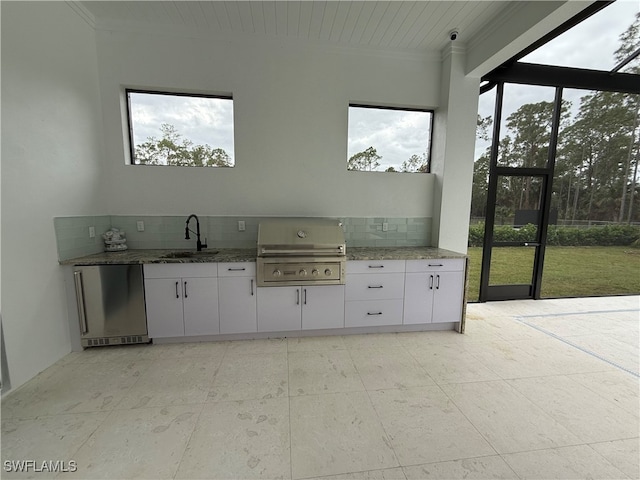 kitchen featuring stainless steel refrigerator, white cabinetry, sink, plenty of natural light, and decorative backsplash