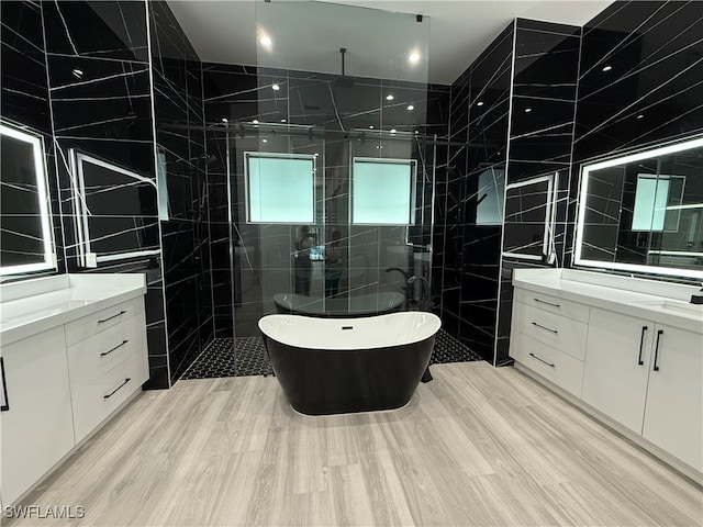 bathroom with plus walk in shower, vanity, hardwood / wood-style flooring, and tile walls