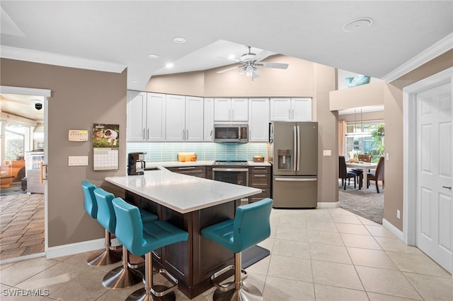 kitchen with kitchen peninsula, appliances with stainless steel finishes, white cabinets, and a wealth of natural light