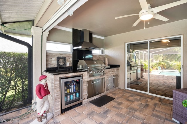 kitchen featuring ceiling fan, wall chimney range hood, and beverage cooler