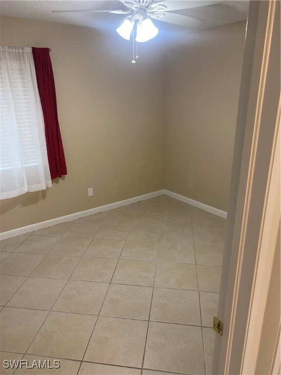 tiled spare room featuring ceiling fan